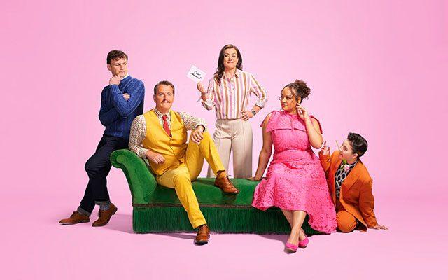 A group of five people sitting on and around a green sofa, set against a pink background.