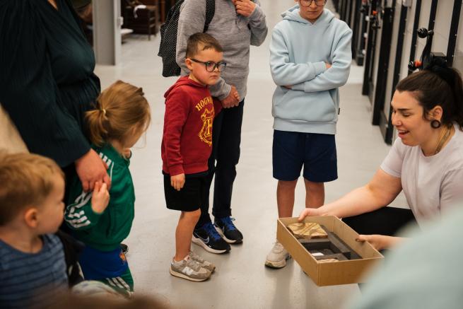 A curator holding a box of ancient tiles in front of a tour group