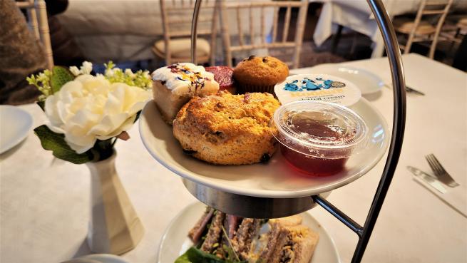 An afternoon tea stand with scones and jam on top