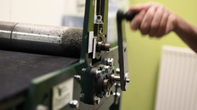 A etching press being wound by hand