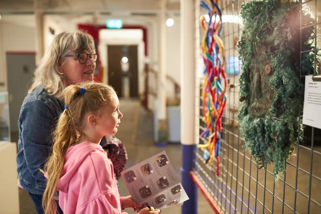 Photograph of a woman and child looking at a woven tapestry