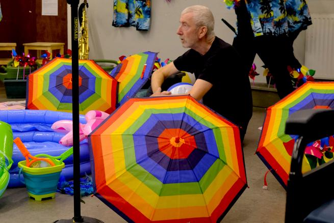 John Poulter in rehearsal with rainbow umbrellas with The Performance Ensemble