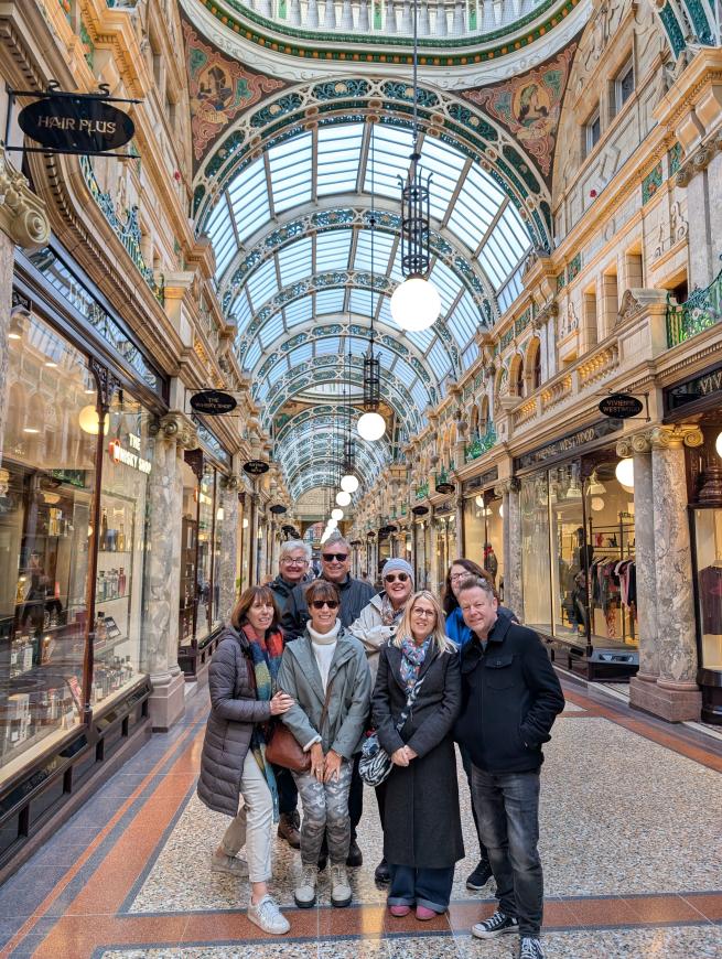 Tour guests inside a shopping arcade that is decorated in ornate Victorian style