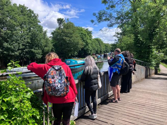People on a bridge looking at canal boats