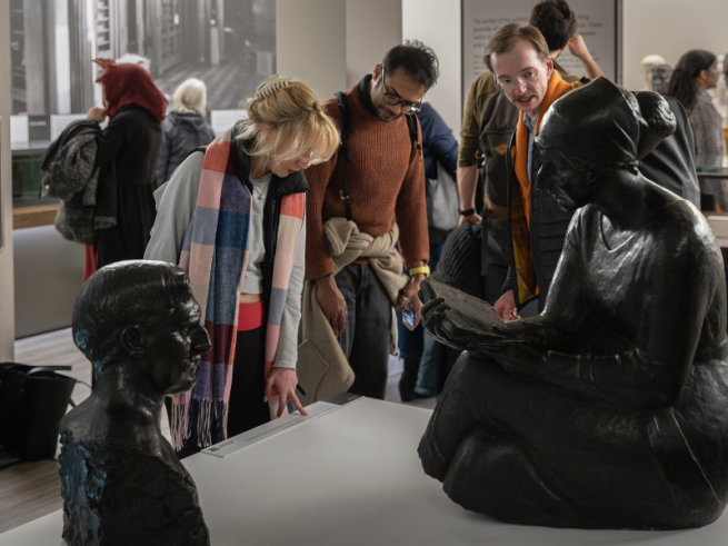 People stood in a museum looking at two bronze sculptures on a white plinth.