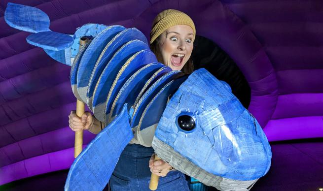 An excited lady holding a whale puppet