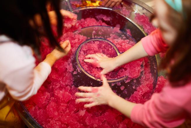 Two children taking part in a hands-on science experiment with a pink substance.