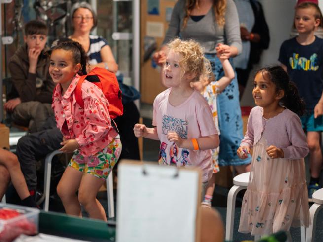 3 children taking part in a workshop, smiling at someone out of frame