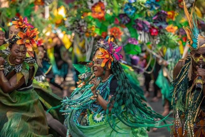 Green costumed dancers smiling in Carnival attire