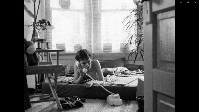 Image of young man on bed answering phone