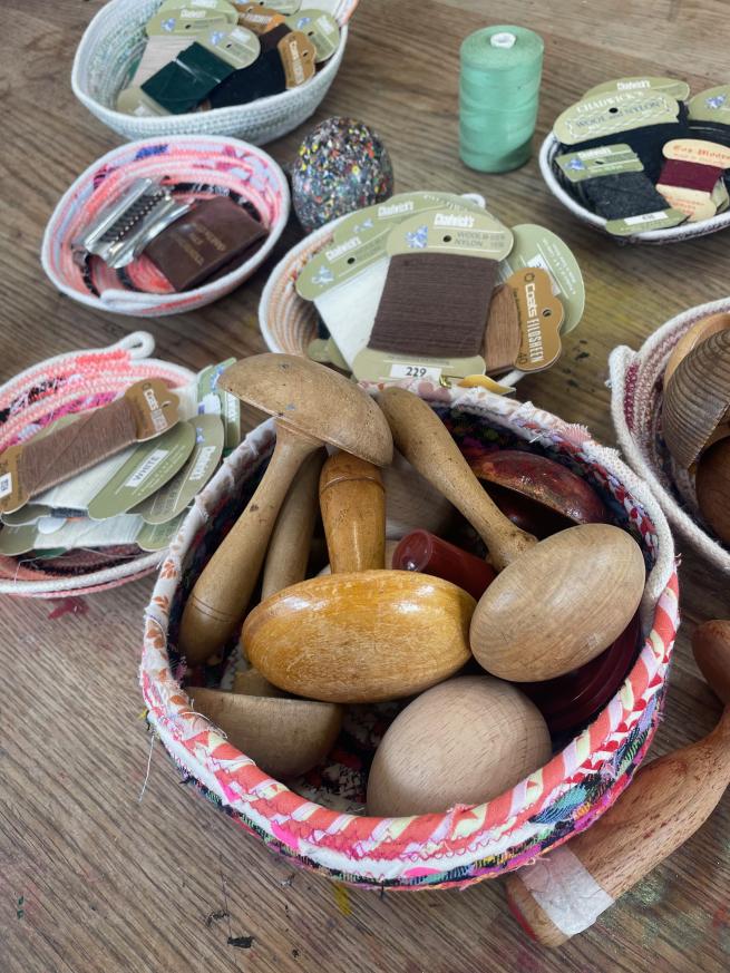 Image shows stitched baskets with darning mushrooms and yarns in them.