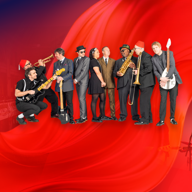 A group of musicians all dressed in black, some holding brass instruments, stood on a red background.