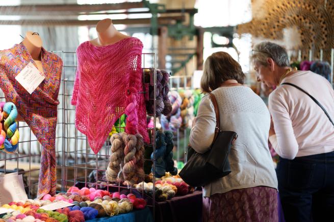 Two people browsing wool clothing stalls