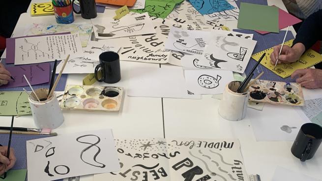 a table with pieces of paper with illustrations on and craft materials