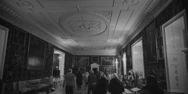A black and white image of a tour in the picture gallery at Temple Newsam