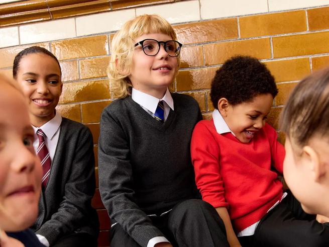 A group of children smiling wearing school uniform
