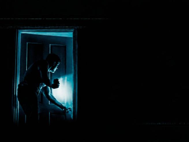 Dark room, man creeping through door with a flash light 