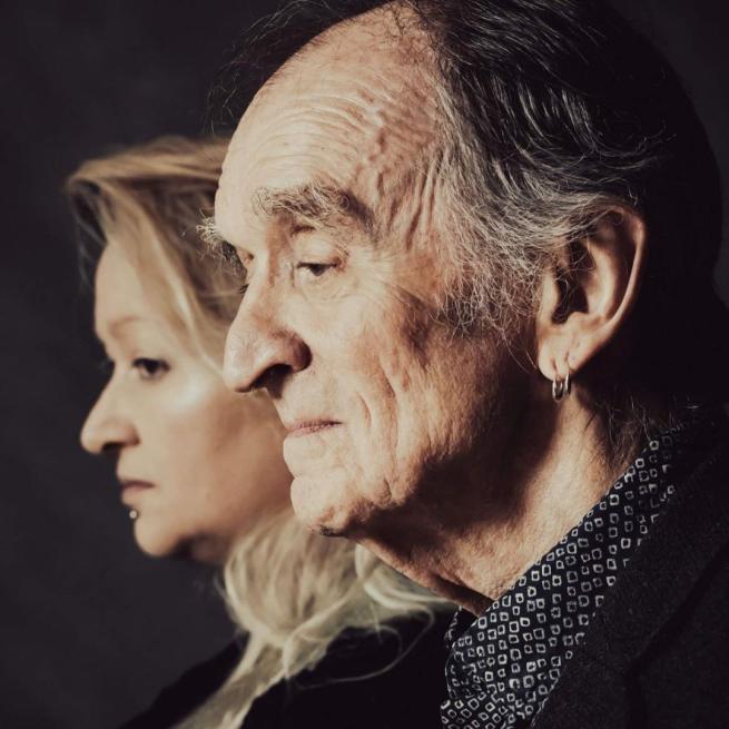 Martin Carthy and Eliza Carthy stand alongside each other in profile, holding neutral expressions under dramatic lighting. 