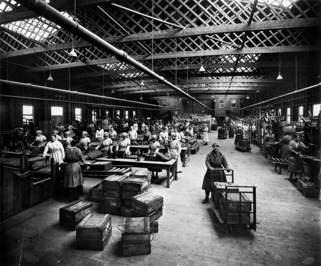 Black and white photograph of the inside of a busy munitions factory.