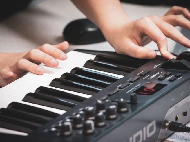 someone using both hands to play a keyboard sampler