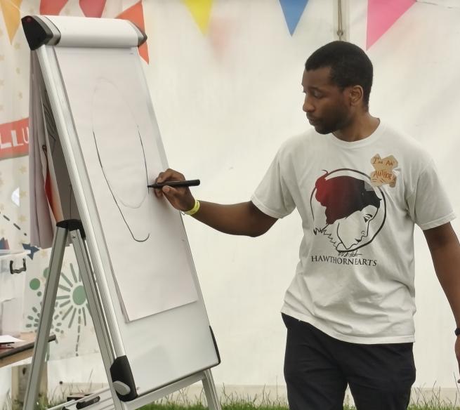Nathan from Hawthornearts draws a face on a flipchart board