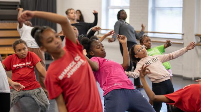 Group of young people in different coloured t-shirts in a dance class
