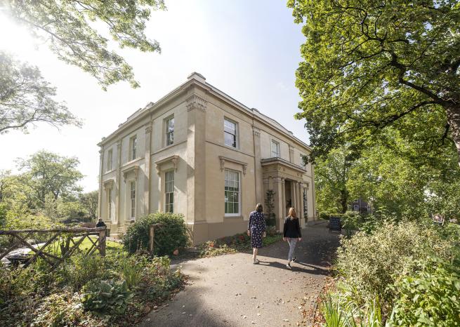 Elizabeth Gaskell's House in sunshine with two people walking up to it.