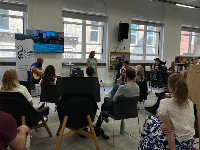 group sat listening to singer accompanied by 2 guitarists