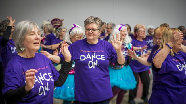 A group of women in 'Dance On' T-shirts dance together