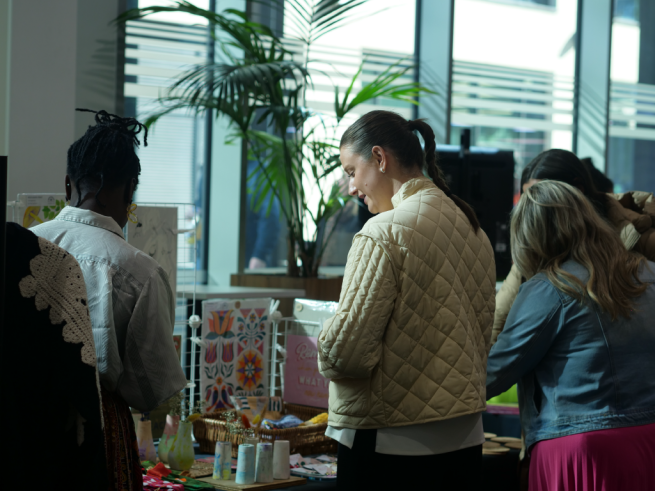 The picture is a market stall and shoppers buying items.