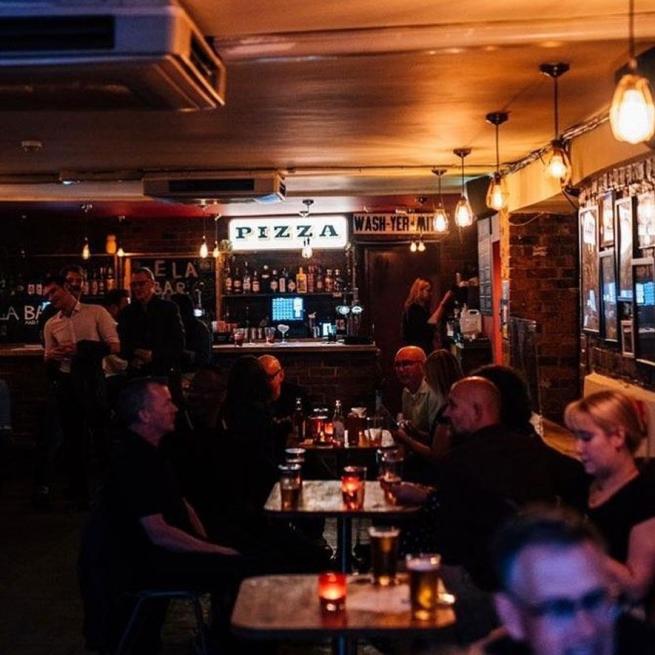 Sela Bar customers sitting down enjoying pints.