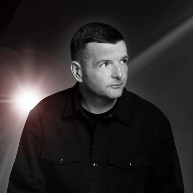 Kevin Bridges in a dark setting with a beam of light.