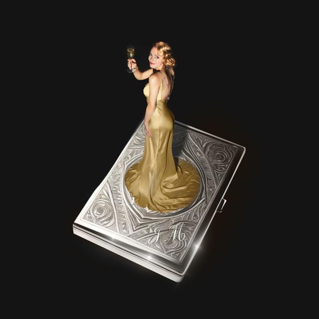 A glamorous blonde lady with shiny blonde hair and flowy silk dress stands atop a silver podium and raises a champagne flute against a stark black background