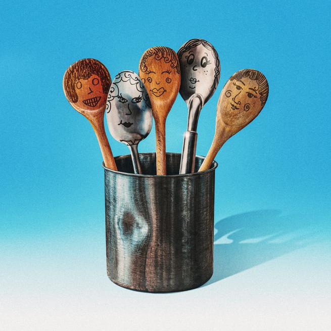 In a tin pot, several silver and wooden spoons with comic faces illustrated in black pen.
