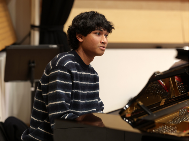 A young man sat at a grand piano.