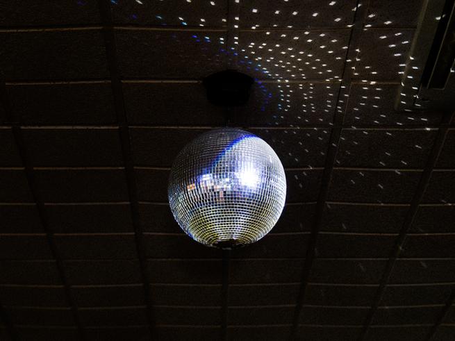 Disco ball on a dark ceiling, casting scattered light reflections.