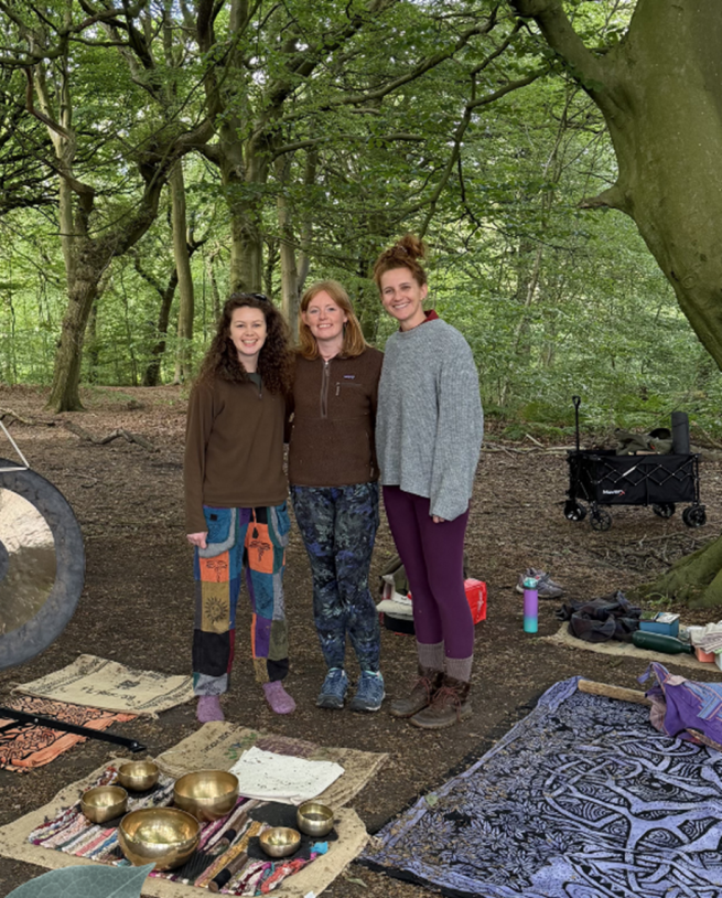 three women smiling in the woods surrounded by instruments