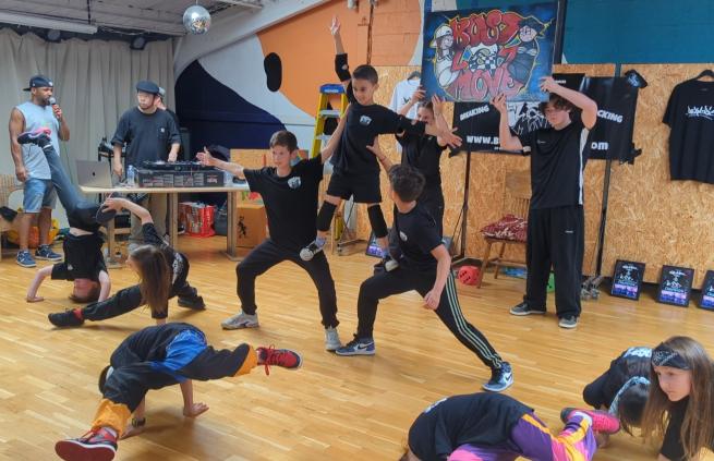 A group of kids are captured mid-performance at the Bust A Move festival, showcasing their breaking routine