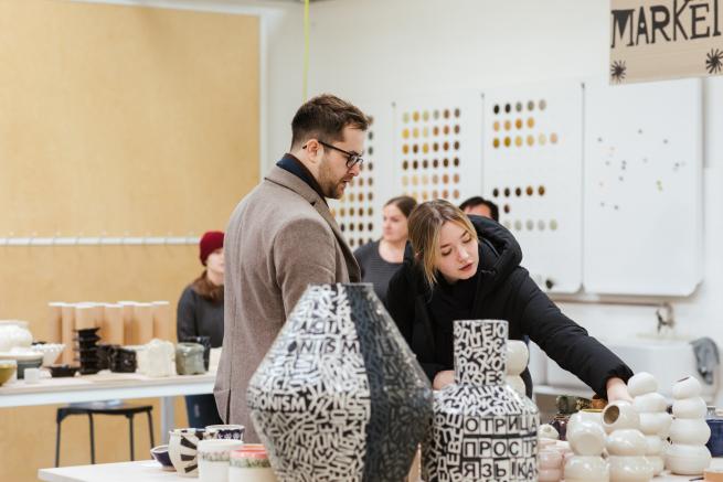 A woman and man browsing the stalls of pottery.