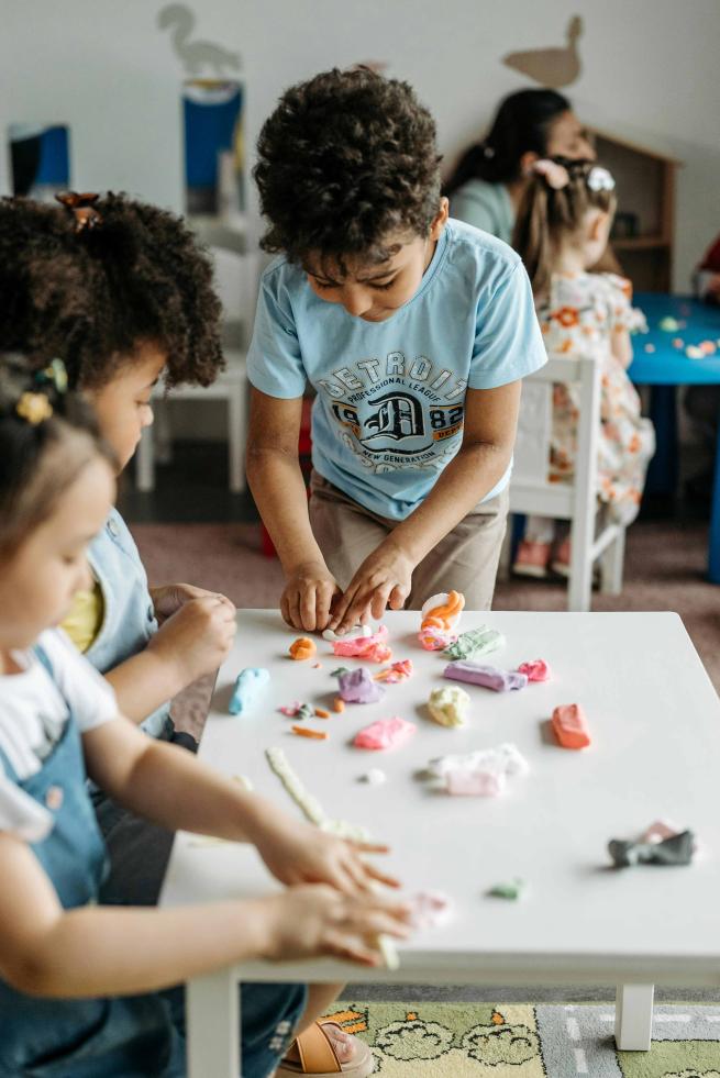 Children playing with clay, making animal shapes.