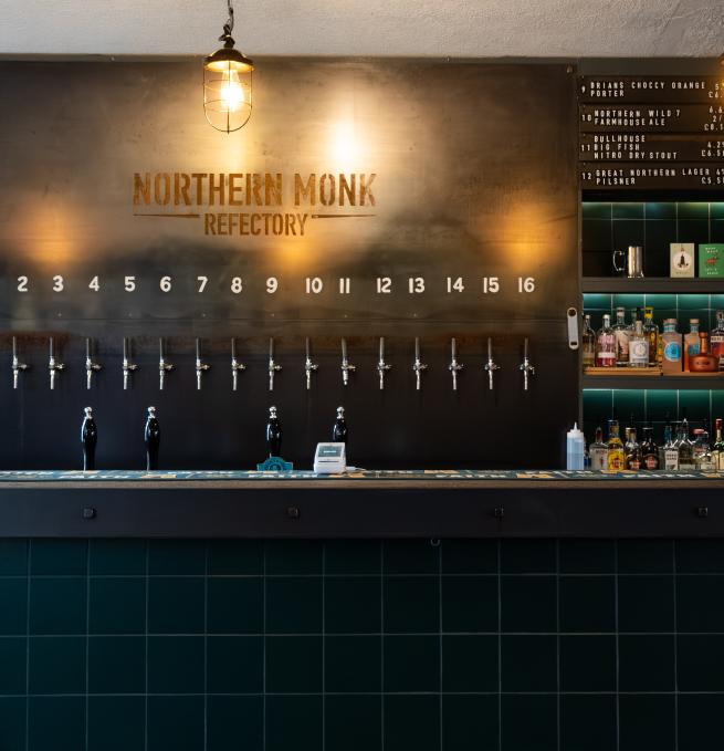 A view of the bar at Northern Monk Refectory Leeds, with green tiles and a steel back bar.