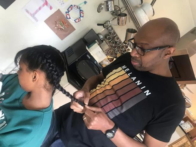Errol, founder of Leeds Dads plaiting his child's hair