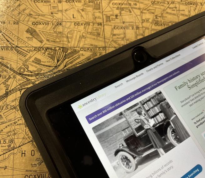 An ipad open on the Ancestry website home page with a map of Leeds in the background.