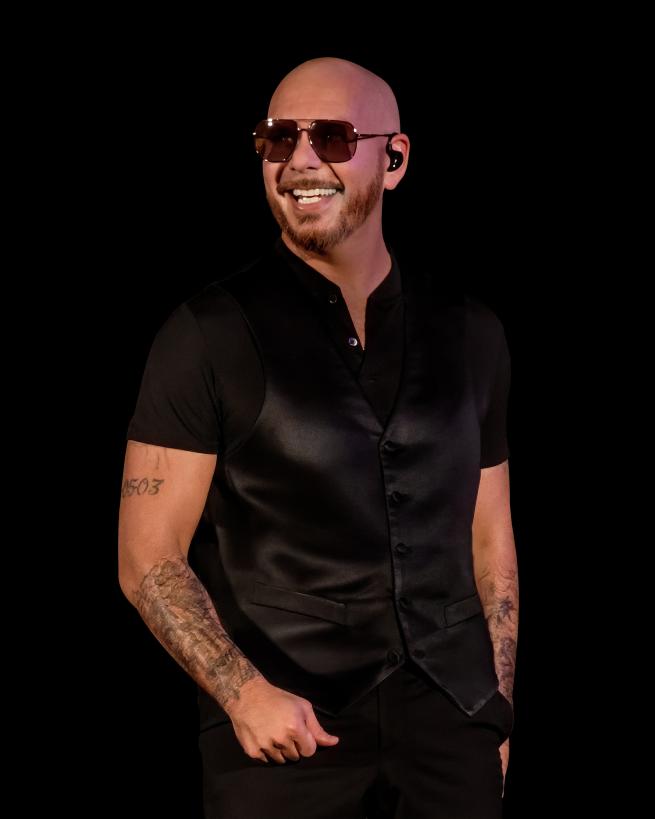 a bald man with sunglasses and tattooed arms wearing all black 