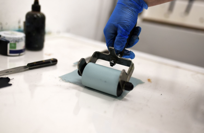 An ink roller being used to roll out light blue ink.