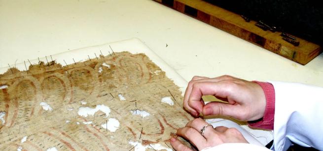 A picture of someone's hands conserving a fragile museum object. 