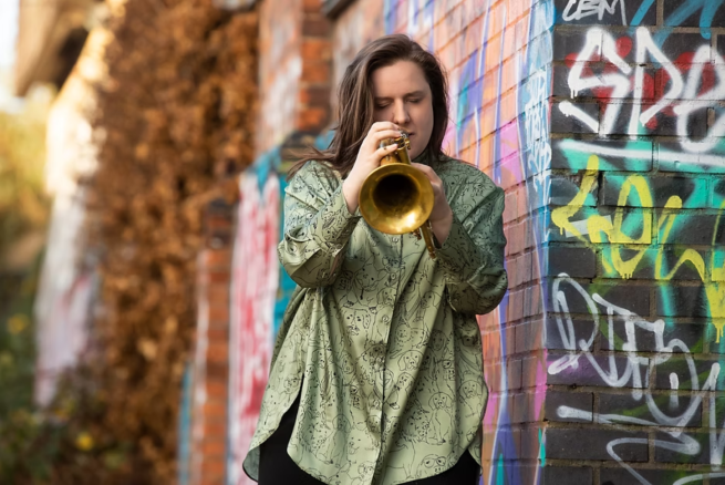 A woman in a green shirt playing a flugel horn.