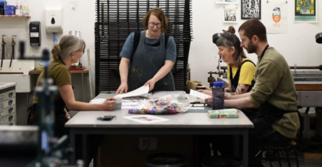 Four artists sat around a table in a print studio 