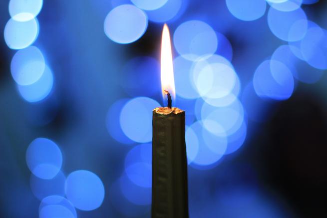 Image shows a lit candle against a blue background