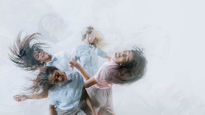 An image of four people whipping their hair dancing. 